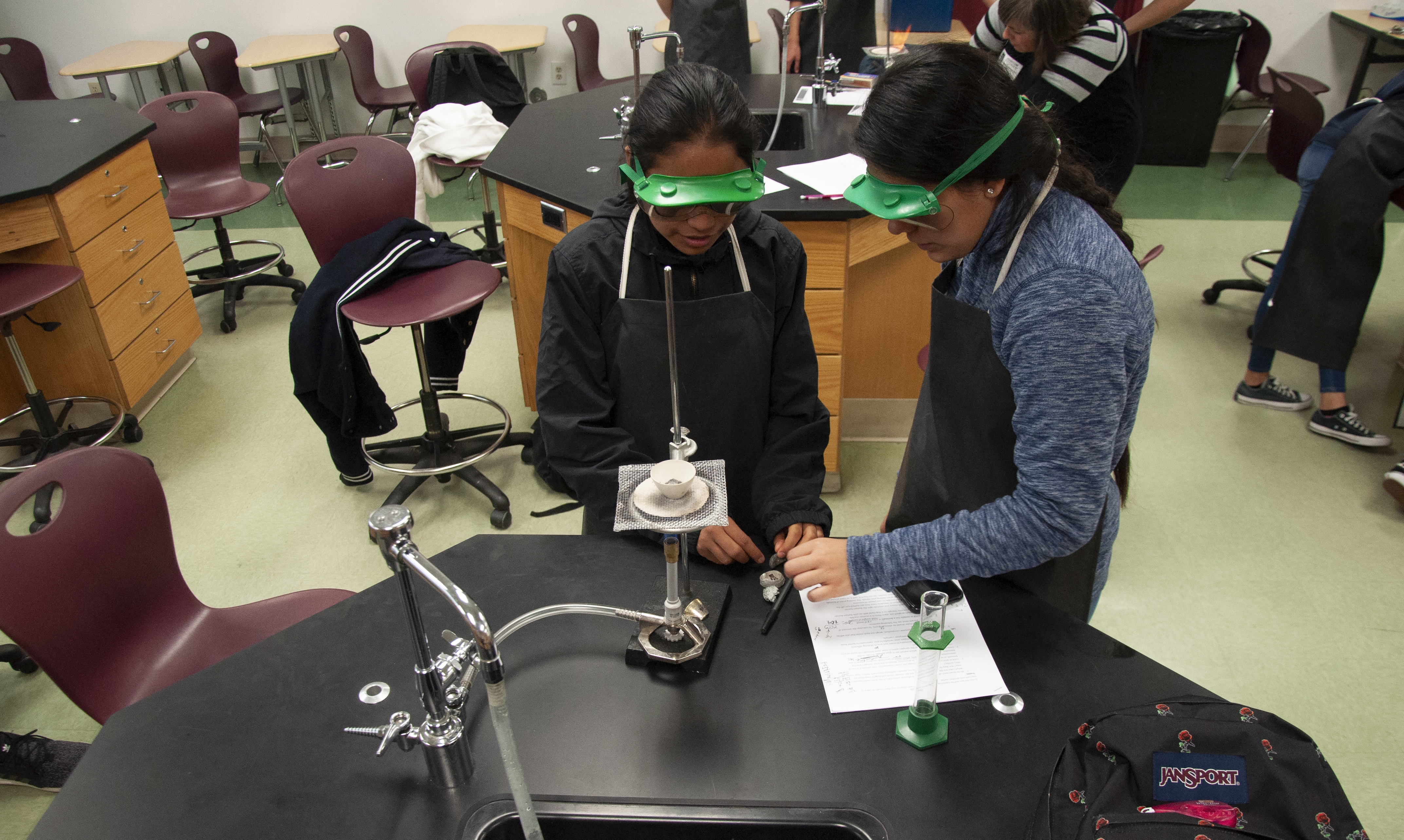 Two students begin melting their alloy test compositions to compare against the unknown sample.